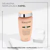 A bottle of Kerastase Curl Manifesto shampoo is displayed on a white pedestal, with text overlays describing its benefits and target hair type. Produktbild-Vorschau