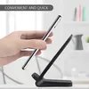 A hand is holding a silver smartphone above a black wireless charging stand. Produktbild-Vorschau