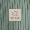 A close-up of a beige label with a bear logo and the brand name "MISIOO" on a green corduroy background. Podgląd zdjęcia produktu