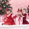 Two young girls are playing with dolls in a festive, pink-themed setting with a Christmas tree and gifts. Produktbild-Vorschau