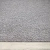 A close-up view of a gray rug with a textured surface, placed on a light wooden floor. Produktbild-Vorschau