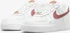 A pair of white Nike Air Force 1 '07 Essential sneakers with rose gold accents. Produktbild-Vorschau