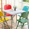 A square table with four chairs around it, set up indoors near a window. Produktbild-Vorschau
