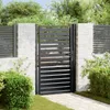 A black metal garden gate is shown in an outdoor setting, with a stone pillar and fence on either side. Lush green bushes and trees form the background. Náhled obrázku produktu