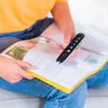 A person is holding a scanning pen over an open book. Náhľad obrázku produktu