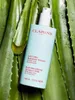 A bottle of Clarins Body-Smoothing Moisture Milk is placed on aloe vera leaves. Náhľad obrázku produktu