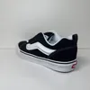 A side view of a single black Vans sneaker with a white stripe. Voir les images du produit