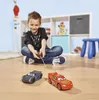 A young boy is playing with remote-controlled cars on the floor. Anteprima dell’immagine prodotto