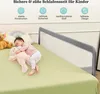A baby sleeping on a bed next to a bed rail, with stuffed animals and a rainbow pillow. Voir les images du produit