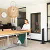 A woman is working on her laptop at a dining table in a modern living room with a fireplace. Produktbild-Vorschau