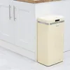 A cream-colored retro-style trash can with a sensor lid is placed next to white kitchen cabinets. Náhled obrázku produktu