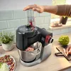 A person is using a Bosch food processor in a kitchen setting, with vegetables and herbs visible. Produktbild-Vorschau