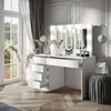 A modern white vanity table with a lighted mirror, makeup products, and decorative items, set in a bright room with large windows and curtains. Náhled obrázku produktu