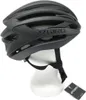 A black Giro Syntax 12 adult cycling helmet is displayed on a white mannequin head, with a product tag in the lower right corner. Náhled obrázku produktu