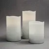 Three LED candles of varying heights are arranged on a plain gray surface. Produktbild-Vorschau