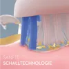 Close-up of an electric toothbrush head cleaning teeth, with small yellow particles representing plaque or debris. Anteprima dell’immagine prodotto