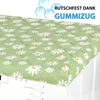 A close-up view of a green quilted cover with a daisy pattern, placed on top of a white washing machine. Anteprima dell’immagine prodotto