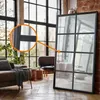 A large mirror with a grid design is placed in a living room setting, reflecting a sofa and windows. Podgląd zdjęcia produktu