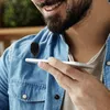A man is holding a smartphone and has a small microphone clipped to his shirt. Podgląd zdjęcia produktu