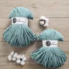 Two spools of teal macrame cord are laid out on a wooden surface, with cotton bolls scattered around. Náhled obrázku produktu