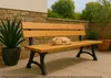 A cat sleeping on a wooden park bench on a patio. Produktbild-Vorschau