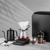 A coffee brewing set is displayed on a table with a gray background. Voir les images du produit