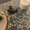 A table runner with gold stars is decorated with pine cones and a candle, suggesting a festive table setting. Produktbild-Vorschau