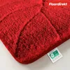 A close-up of a red bath mat with a textured surface and a label attached. Produktbild-Vorschau