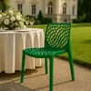 A green chair is placed on a patio next to a table set for a meal, with a building in the background. Produktbild-Vorschau
