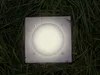 A square solar-powered ground light is embedded in grass. Produktbild-Vorschau