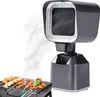 A close-up view of a portable grill with food, with a smoke extractor device in the background. Produktbild-Vorschau