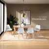 A dining room setting with a wooden table and four white chairs, a plant, and artwork on the wall. Náhled obrázku produktu