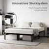 A bedroom scene featuring a black metal bed frame with a white mattress and pillows. Voir les images du produit