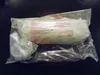 A product wrapped in clear plastic packaging, lying on a dark surface. Produktbild-Vorschau
