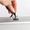A hand is holding two keys over a silver case lock. Podgląd zdjęcia produktu