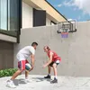 Two men playing basketball outdoors against a concrete wall with a basketball hoop mounted. Produktbild-Vorschau