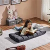 A young girl is lying on a fluffy rug, reading a book while wearing headphones. There are stuffed animals and storage boxes in the background. Podgląd zdjęcia produktu