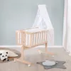 A baby crib with a canopy and bedding, placed on a wooden floor next to a panda plush toy and a star-shaped rug with a cloud pillow. Produktbild-Vorschau
