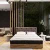 A bedroom scene with a large bed as the focal point, a sofa in the background, and a vertical wooden partition with greenery. Produktbild-Vorschau