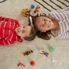 Two children lying on a rug with toys. Podgląd zdjęcia produktu