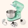 A mint green stand mixer with its bowl and three attachments laid out in front of it, set against a plain light beige background. Produktbild-Vorschau