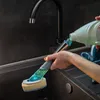 A person is pouring dish soap into a dish brush with a sponge. Anteprima dell’immagine prodotto