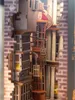 A detailed close-up of a miniature model of Diagon Alley, featuring intricate building facades, windows, and hanging lanterns. Produktbild-Vorschau