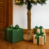 Christmas tree with gifts underneath, set against a wooden door and white wall. Produktbild-Vorschau