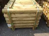 A stack of wooden palisades tied together with green straps. Produktbild-Vorschau