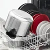 A close-up view of a dishwasher rack filled with kitchenware, including a large stainless steel pot and several plates. Podgląd zdjęcia produktu