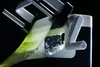 A close-up shot of a vegetable slicer with a long slice of cucumber being processed. Produktbild-Vorschau