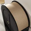 Close-up view of the curved top of a black cabinet with a tan linen-like fabric band. Voir les images du produit