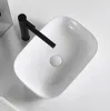 A white ceramic vessel sink with a black faucet. Produktbild-Vorschau