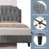 A close-up view of a grey upholstered bed frame with a mattress and bedding, accompanied by descriptive text and circular insets highlighting features. Produktbild-Vorschau
